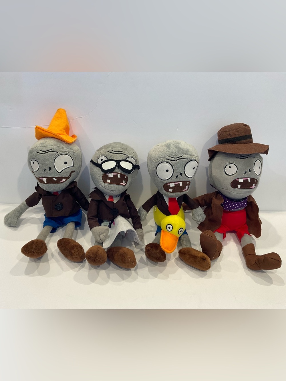This image shows a collection of four Plants vs. Zombies plush zombie toys.